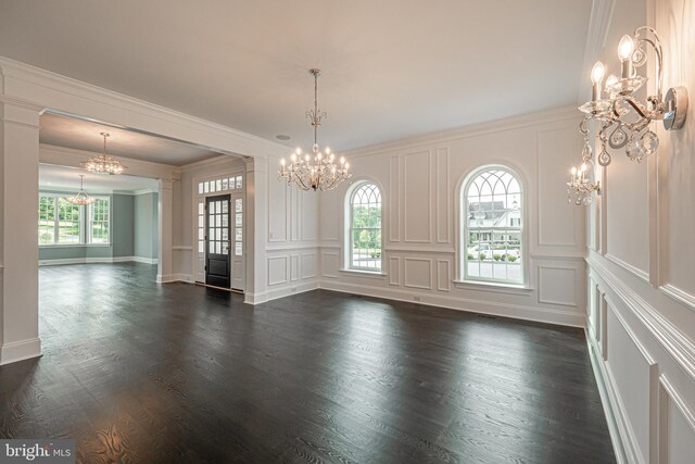 empty room featuring crown molding, dark wood-type flooring, and a notable chandelier