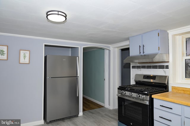 kitchen featuring backsplash, ornamental molding, stainless steel appliances, and light wood-type flooring