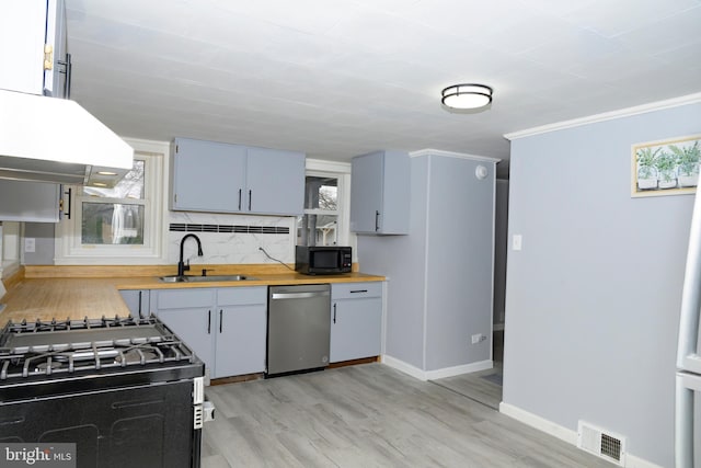 kitchen featuring island exhaust hood, light hardwood / wood-style floors, sink, dishwasher, and butcher block countertops