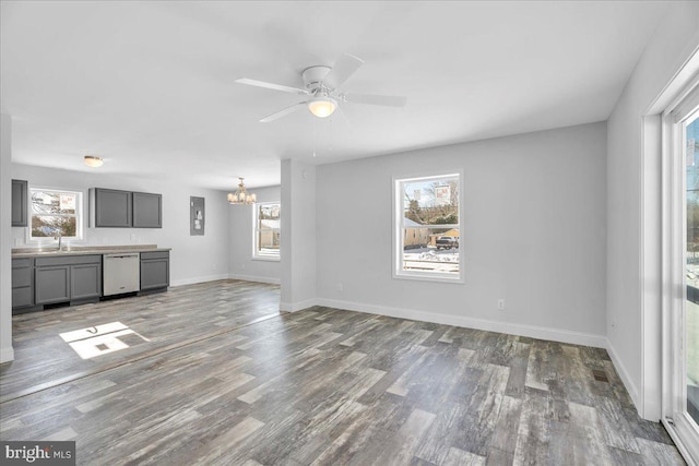 unfurnished living room with hardwood / wood-style floors, ceiling fan with notable chandelier, sink, and a wealth of natural light