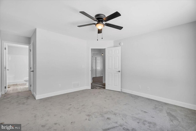 unfurnished bedroom with ceiling fan, ensuite bathroom, and light colored carpet