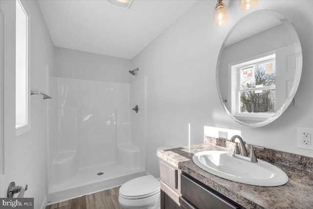 bathroom featuring hardwood / wood-style floors, vanity, toilet, and a shower