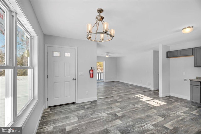 foyer entrance featuring dark hardwood / wood-style floors, a healthy amount of sunlight, and ceiling fan with notable chandelier