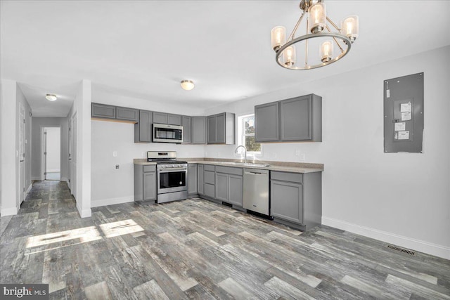 kitchen with appliances with stainless steel finishes, sink, gray cabinets, a notable chandelier, and electric panel