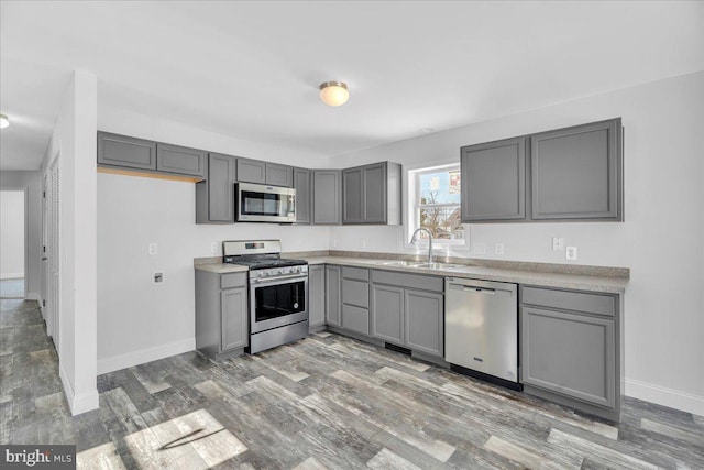 kitchen with gray cabinetry, dark hardwood / wood-style flooring, sink, and stainless steel appliances