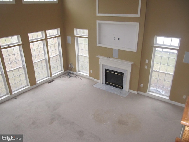 unfurnished living room featuring light carpet and a high end fireplace