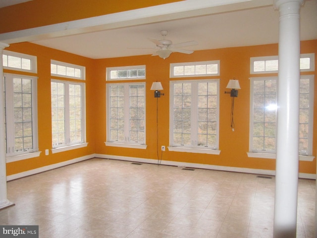 unfurnished sunroom featuring ceiling fan and decorative columns