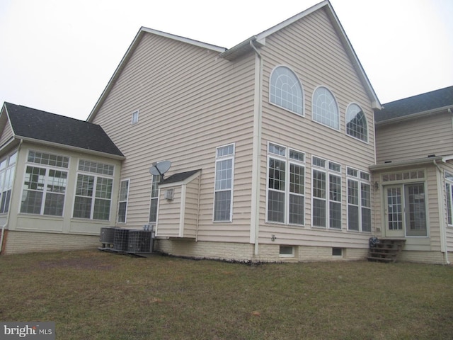 rear view of house featuring a lawn and central AC