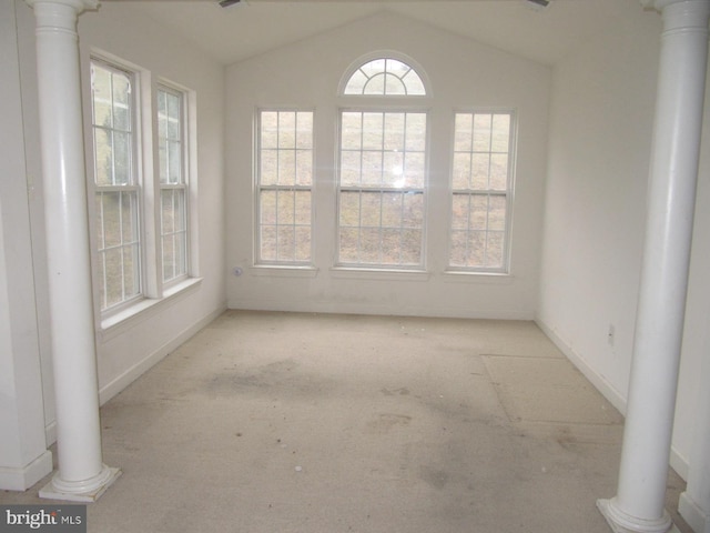 empty room with decorative columns and vaulted ceiling