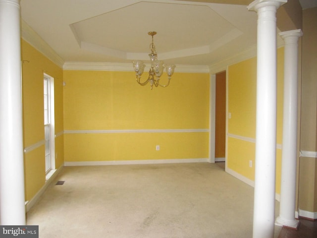 carpeted empty room featuring a chandelier, ornamental molding, decorative columns, and a tray ceiling