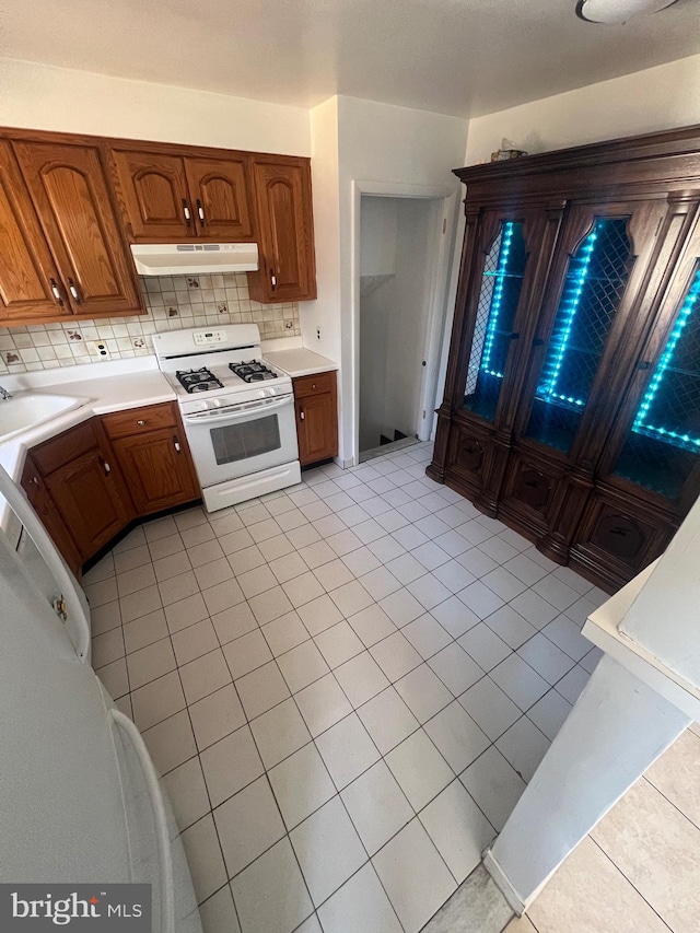 kitchen with white range with gas stovetop, sink, light tile patterned floors, and tasteful backsplash