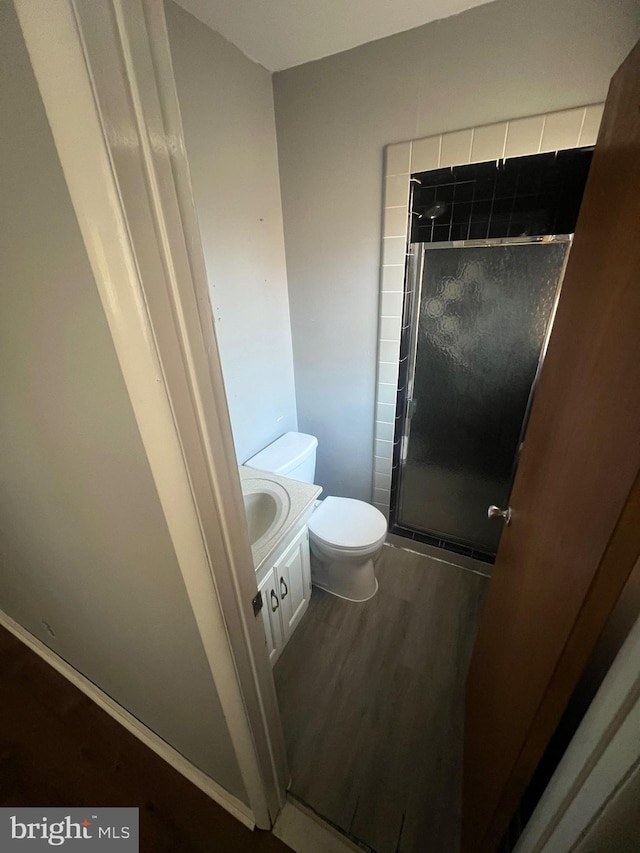 bathroom featuring hardwood / wood-style floors, vanity, toilet, and a shower with shower door