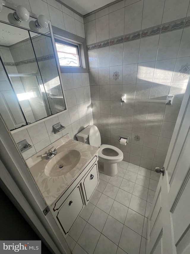 bathroom with tile patterned floors, vanity, tile walls, and toilet