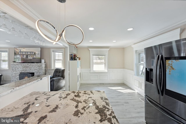 bedroom with crown molding, a fireplace, light hardwood / wood-style floors, and stainless steel refrigerator with ice dispenser