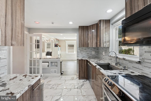 kitchen featuring decorative backsplash, light stone counters, sink, and stainless steel appliances