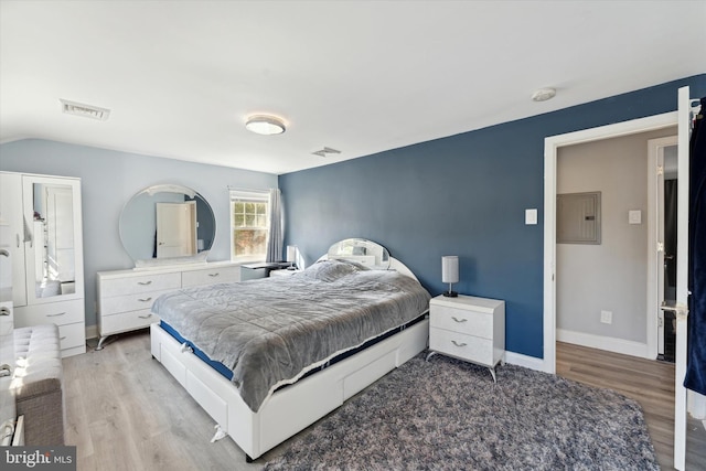 bedroom with electric panel and light hardwood / wood-style flooring