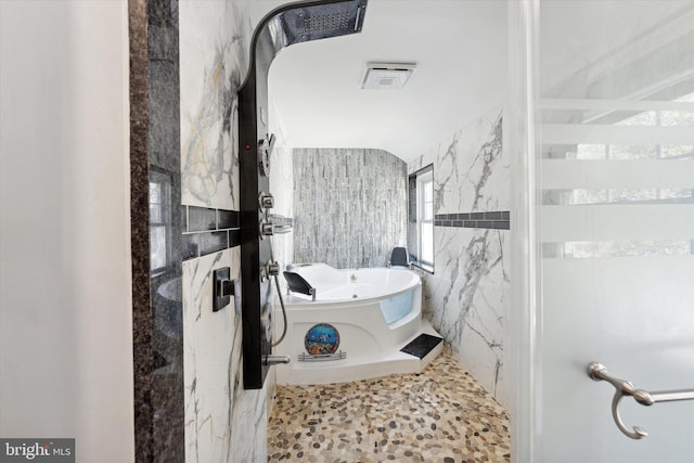 bathroom featuring shower with separate bathtub and tile walls