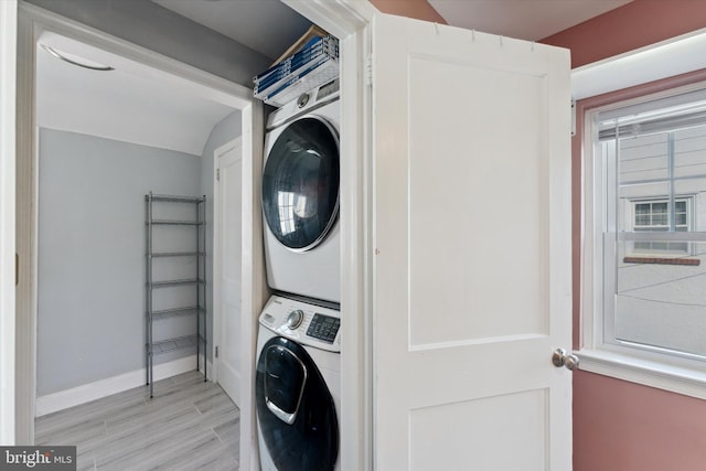 washroom with light hardwood / wood-style floors and stacked washer and dryer