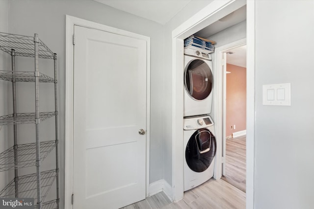 washroom with stacked washer and dryer and light hardwood / wood-style flooring