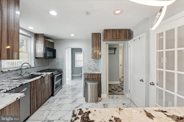 kitchen with light stone countertops, stainless steel appliances, tasteful backsplash, and sink