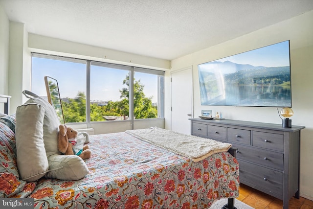 bedroom featuring a textured ceiling, light hardwood / wood-style floors, and multiple windows