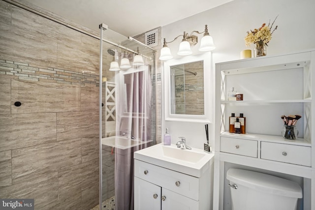 bathroom featuring a tile shower, vanity, and toilet