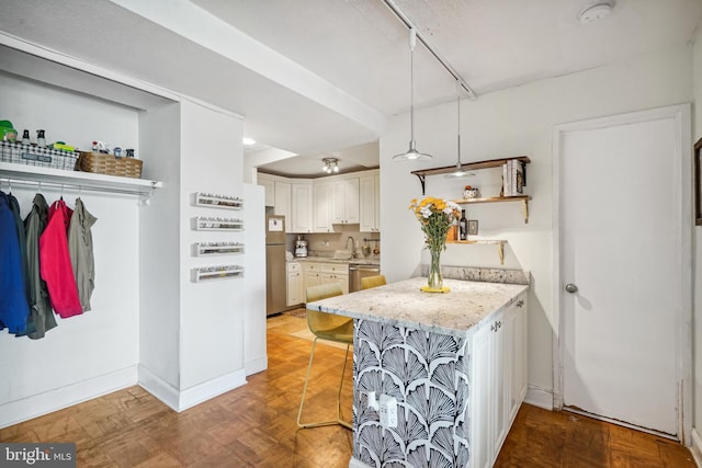 kitchen featuring white cabinetry, light parquet floors, decorative light fixtures, a breakfast bar, and appliances with stainless steel finishes