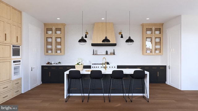 kitchen with stainless steel oven, oven, a kitchen island with sink, decorative light fixtures, and a breakfast bar area