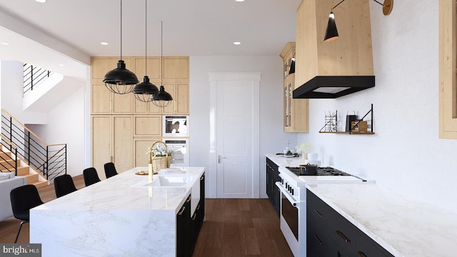 kitchen with hanging light fixtures, premium range hood, light stone counters, a kitchen island with sink, and gas stove