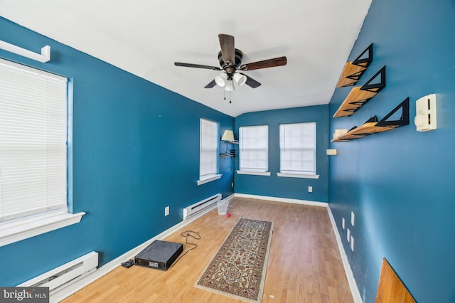 interior space featuring ceiling fan, wood-type flooring, vaulted ceiling, and a baseboard heating unit