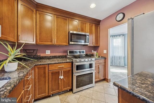 kitchen featuring dark stone countertops, light tile patterned flooring, and appliances with stainless steel finishes