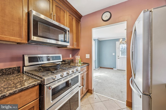 kitchen featuring light carpet, appliances with stainless steel finishes, and dark stone counters