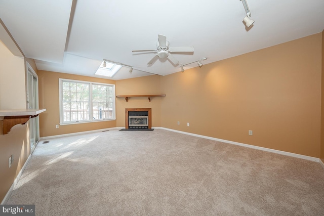 unfurnished living room featuring a skylight, light colored carpet, and rail lighting