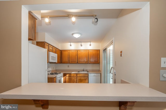 kitchen with sink, white appliances, kitchen peninsula, and rail lighting