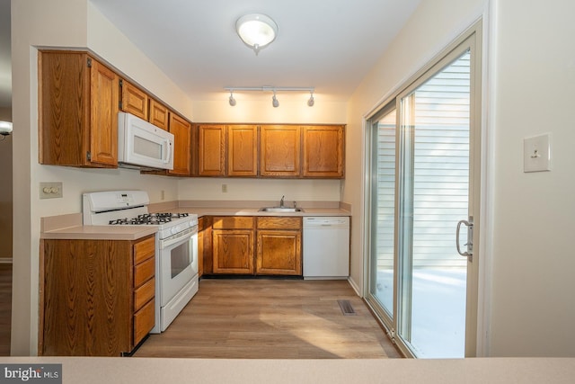 kitchen featuring sink, white appliances, and light wood-type flooring