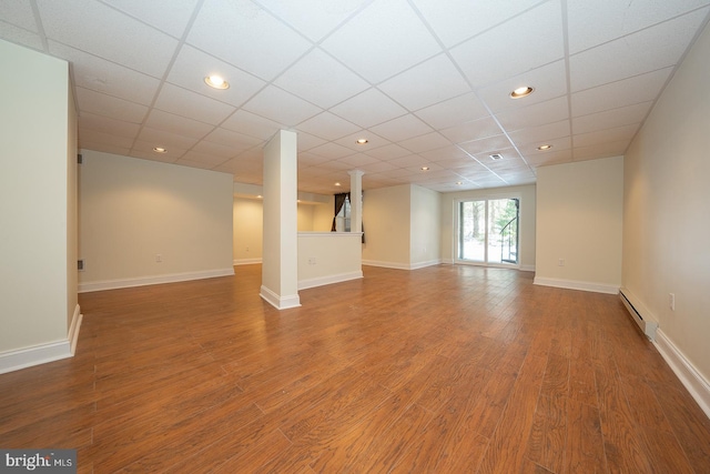 interior space with baseboard heating, wood-type flooring, and a paneled ceiling