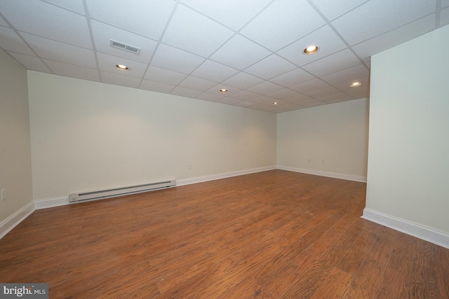 empty room with baseboard heating, a paneled ceiling, and hardwood / wood-style flooring