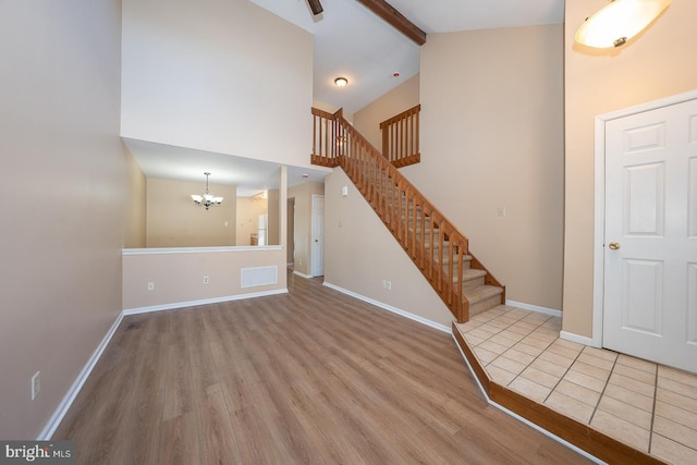 entrance foyer with high vaulted ceiling, beamed ceiling, light hardwood / wood-style flooring, and a notable chandelier