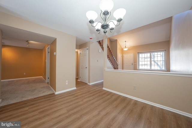 empty room with a notable chandelier and light hardwood / wood-style floors