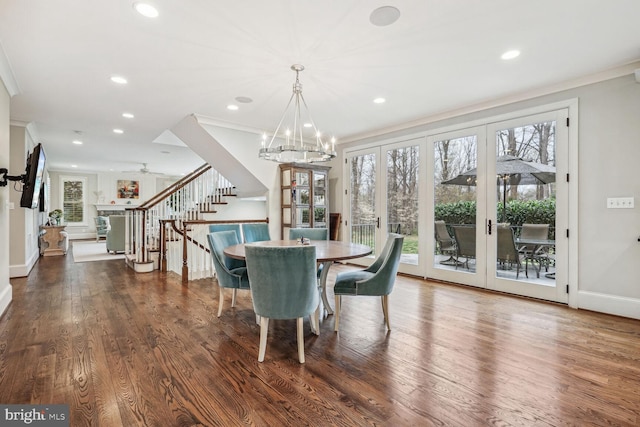 dining space with ceiling fan with notable chandelier, ornamental molding, dark wood-type flooring, and french doors