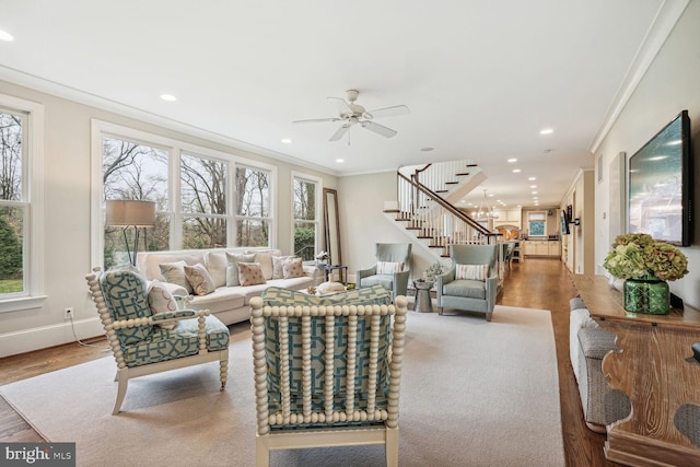 living room featuring ceiling fan with notable chandelier, hardwood / wood-style flooring, and crown molding