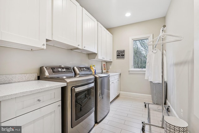 clothes washing area featuring cabinets and washer and dryer