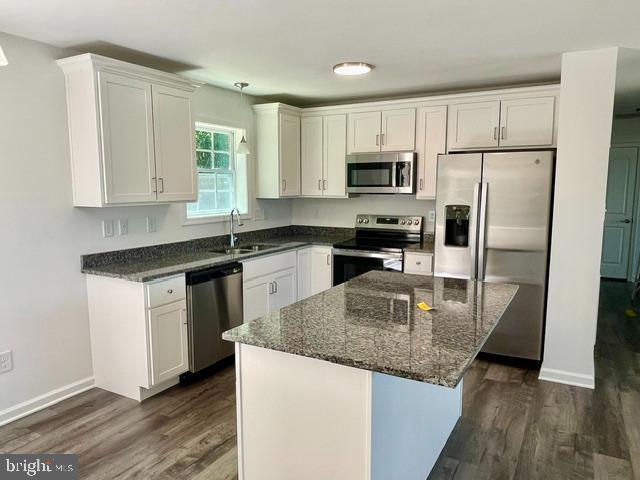 kitchen featuring a center island, sink, appliances with stainless steel finishes, dark hardwood / wood-style flooring, and white cabinetry