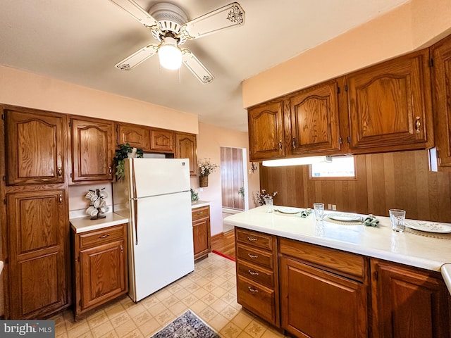 kitchen featuring light countertops, freestanding refrigerator, and brown cabinets