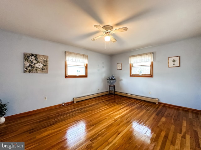 spare room featuring a healthy amount of sunlight, hardwood / wood-style flooring, baseboards, and a baseboard heating unit