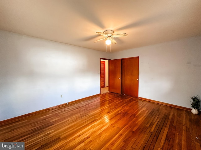 unfurnished bedroom with hardwood / wood-style flooring, ceiling fan, baseboards, and a closet