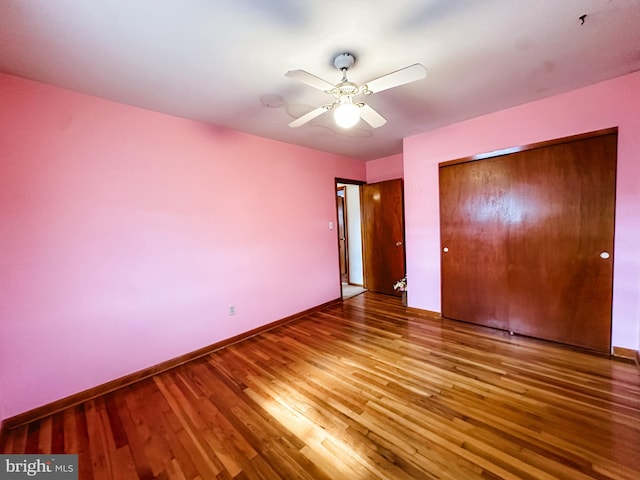 unfurnished bedroom featuring a closet, wood finished floors, a ceiling fan, and baseboards