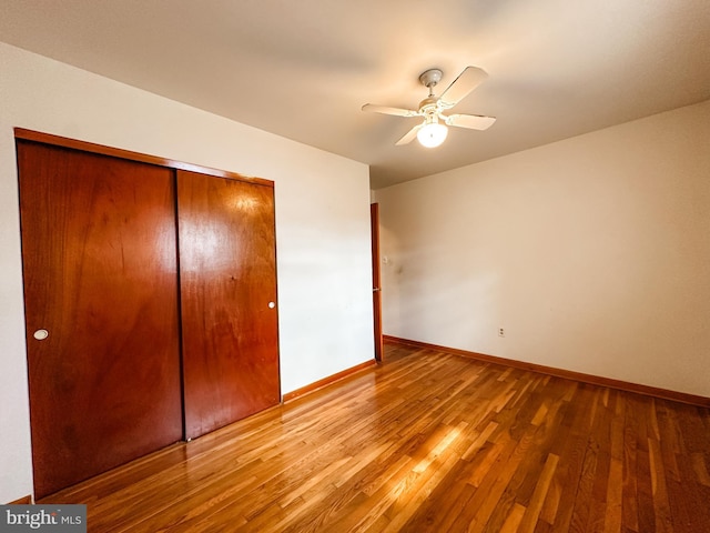 unfurnished bedroom featuring a closet, ceiling fan, baseboards, and wood finished floors