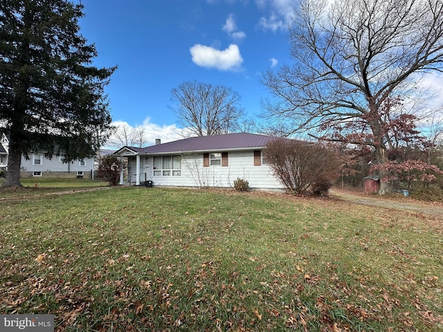 view of front of property featuring metal roof, a chimney, and a front lawn