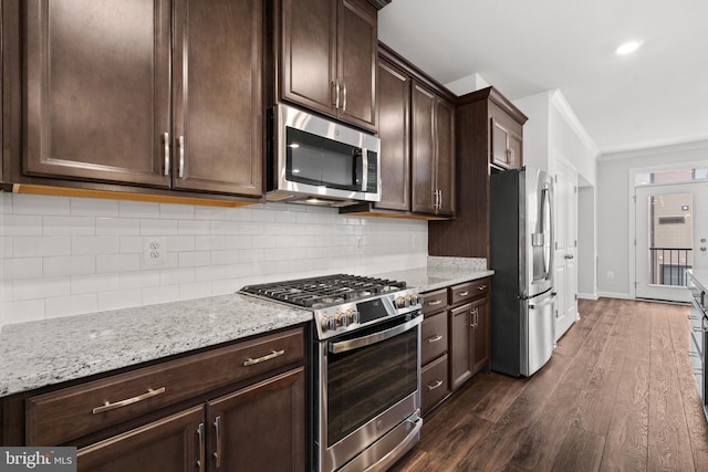 kitchen featuring light stone countertops, dark hardwood / wood-style floors, crown molding, dark brown cabinets, and appliances with stainless steel finishes